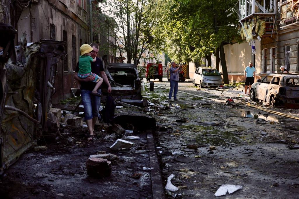 В Одесі через обстріл постраждали медичні заклади: що відомо про наслідки 1 Одесит несе на руках дитину пошкодженою вулицею