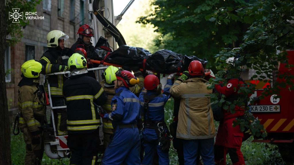 Зруйнований під’їзд, загиблі та поранені люди: які наслідки нічної атаки по Києву 1 Рятувальники виносять тіло загиблої людини з пошкодженого будинку